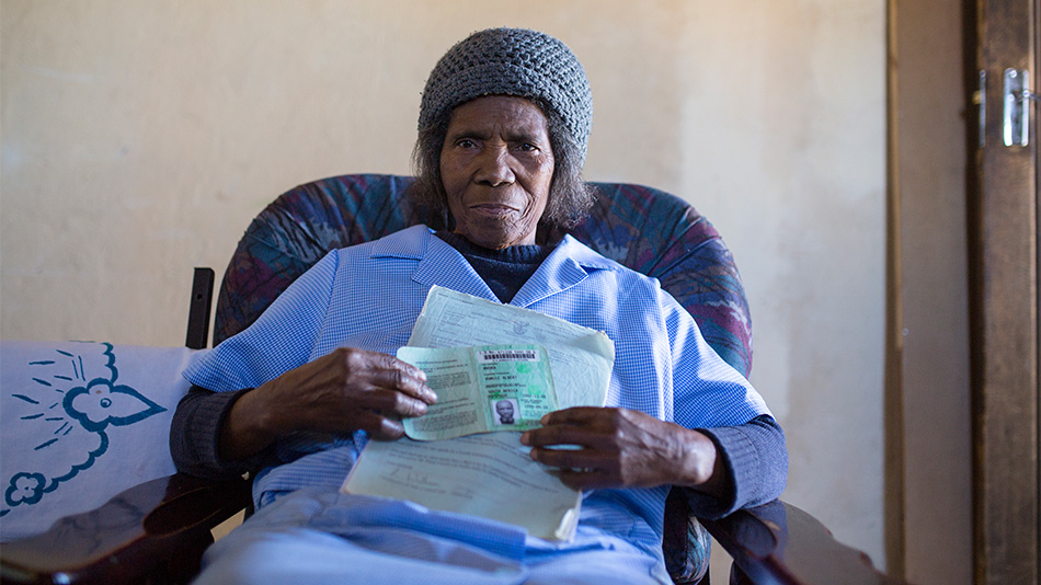 WIDOW: The wife of Albert Mvuka holds up her deceased husband's identity document. Photo: Johanna Chisholm